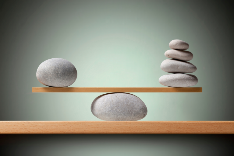 Balanced smooth stones on wooden seesaw demonstrating perfect equilibrium.