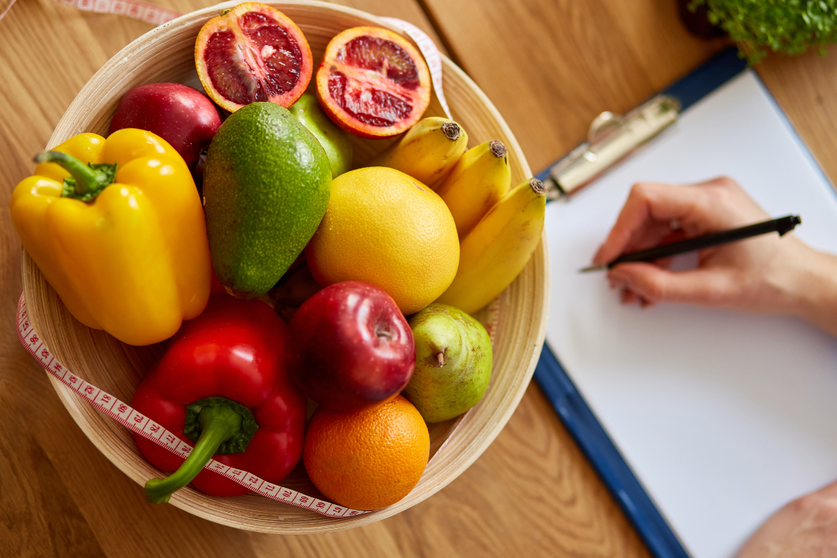 A bowl of healthy foods is placed next to a clipboard.